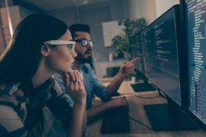 Mann und Frau mit Brille sitzen vor dem Monitor